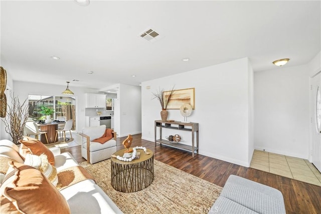 living area featuring wood finished floors, visible vents, and baseboards