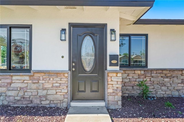 view of exterior entry with stone siding and stucco siding