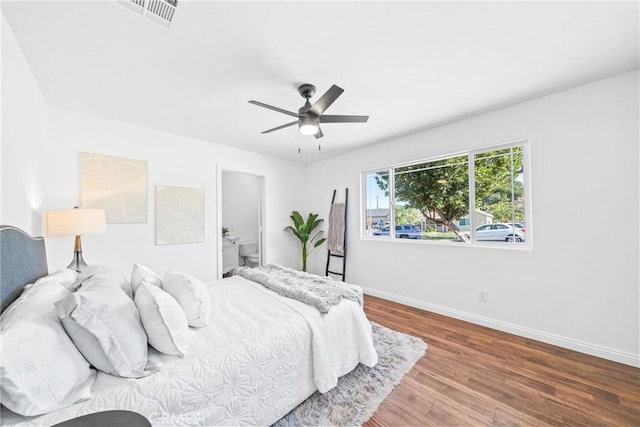 bedroom with a ceiling fan, wood finished floors, visible vents, and baseboards