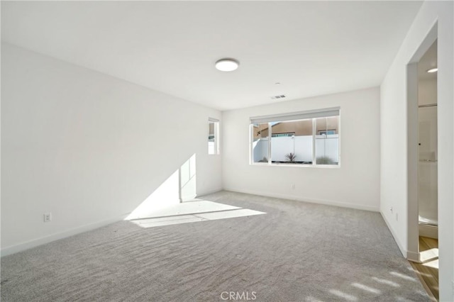 spare room featuring light carpet, baseboards, and visible vents