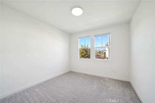 spare room featuring carpet floors and baseboards