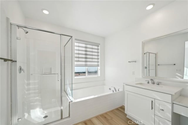 full bathroom with a bath, a shower stall, vanity, and wood finished floors