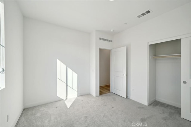 unfurnished bedroom with light colored carpet, a closet, and visible vents