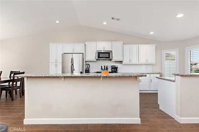 kitchen with visible vents, white cabinets, decorative backsplash, an island with sink, and stainless steel appliances