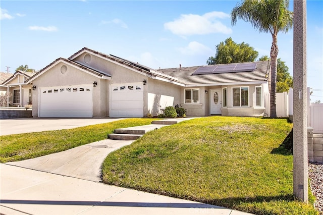 single story home featuring stucco siding, an attached garage, roof mounted solar panels, driveway, and a front lawn