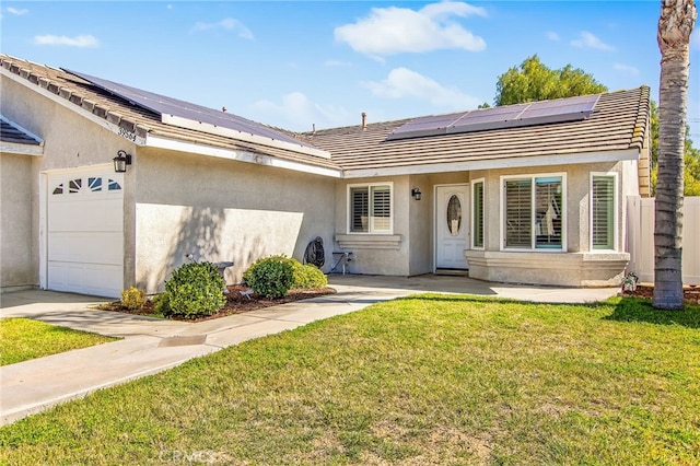 view of front facade with a garage, roof mounted solar panels, a front lawn, and stucco siding