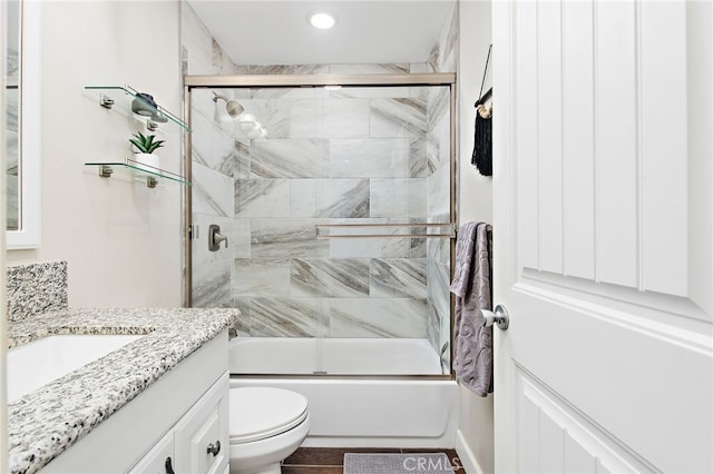 bathroom featuring combined bath / shower with glass door, vanity, and toilet