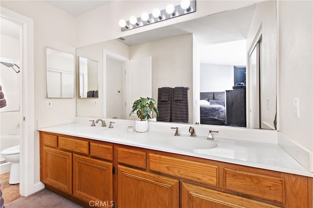 bathroom with double vanity, a sink, toilet, and ensuite bathroom