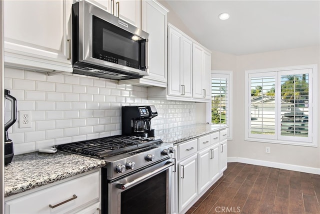 kitchen with dark wood-style flooring, white cabinetry, stainless steel appliances, and light stone counters