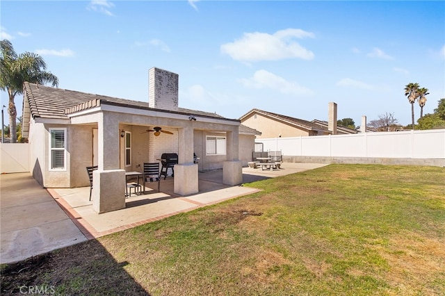 back of house featuring a patio, a fenced backyard, a ceiling fan, a yard, and stucco siding