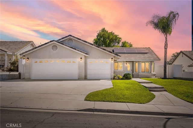 ranch-style house with a garage, concrete driveway, stucco siding, and roof mounted solar panels