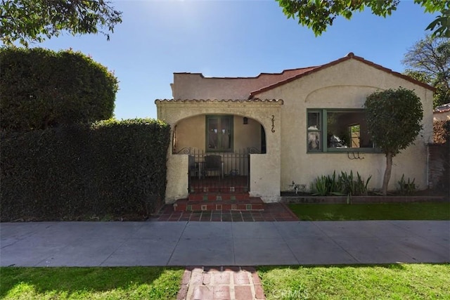 mediterranean / spanish house featuring a fenced front yard, a gate, and stucco siding