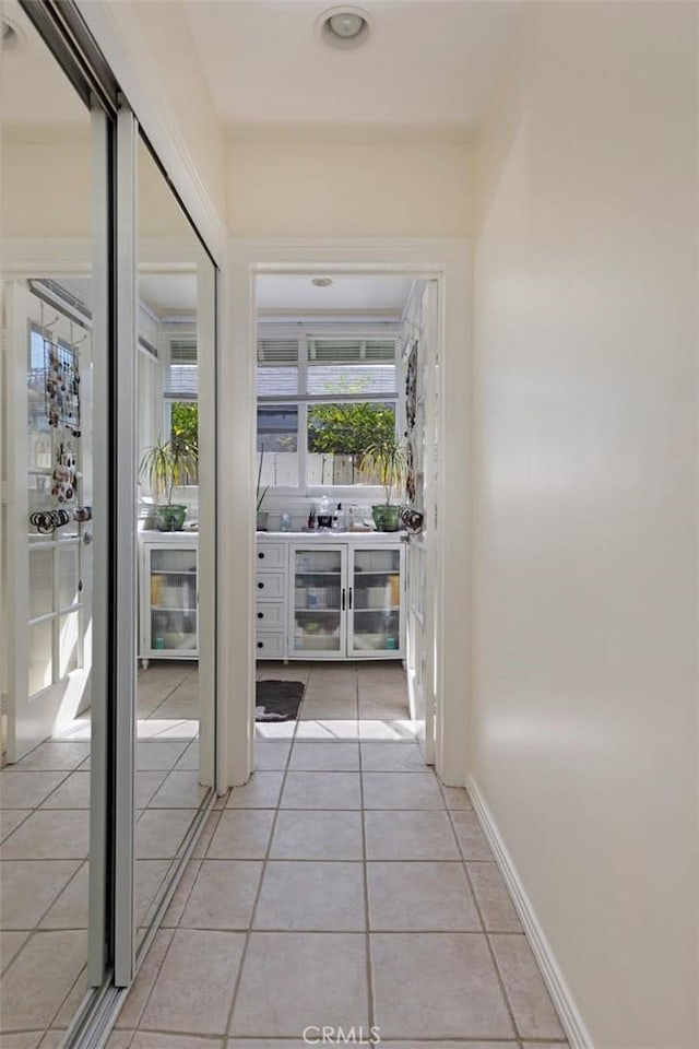 corridor with light tile patterned floors and baseboards