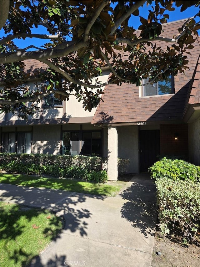 townhome / multi-family property with a shingled roof and stucco siding