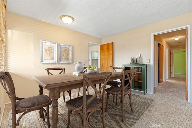 carpeted dining area with a textured ceiling