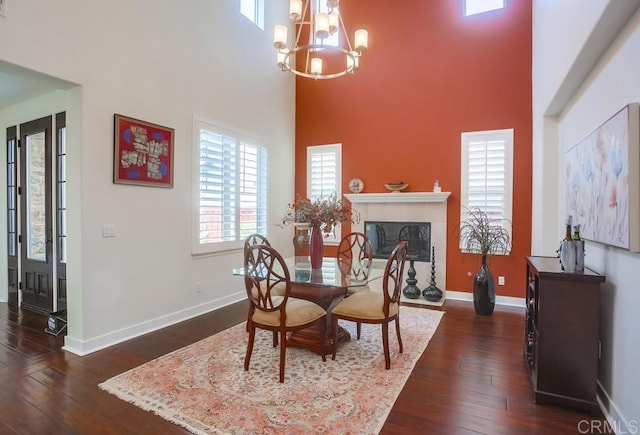 dining room with baseboards, a fireplace with flush hearth, an inviting chandelier, and dark wood-style flooring