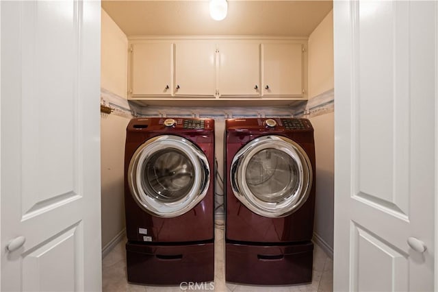 clothes washing area with washing machine and dryer, cabinet space, and light tile patterned floors