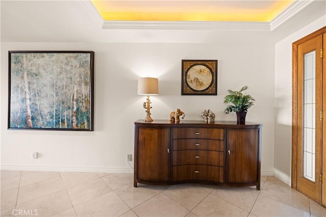 interior space with baseboards, light tile patterned floors, a raised ceiling, and crown molding