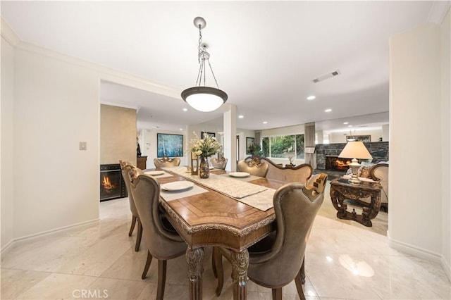 dining room with a warm lit fireplace, baseboards, visible vents, and recessed lighting