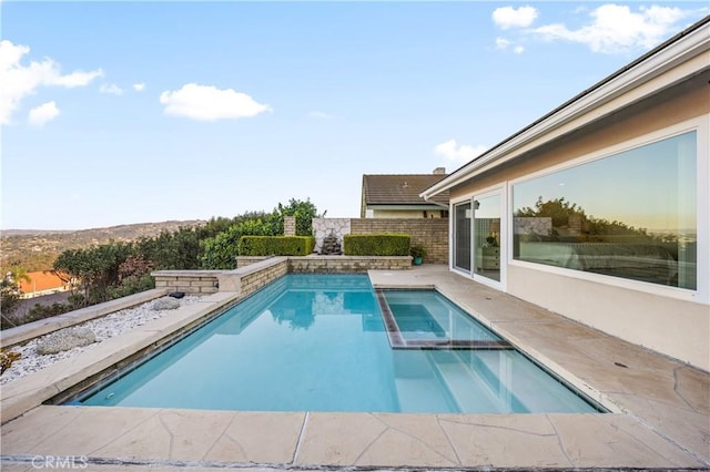 view of pool with a pool with connected hot tub, a patio area, and fence