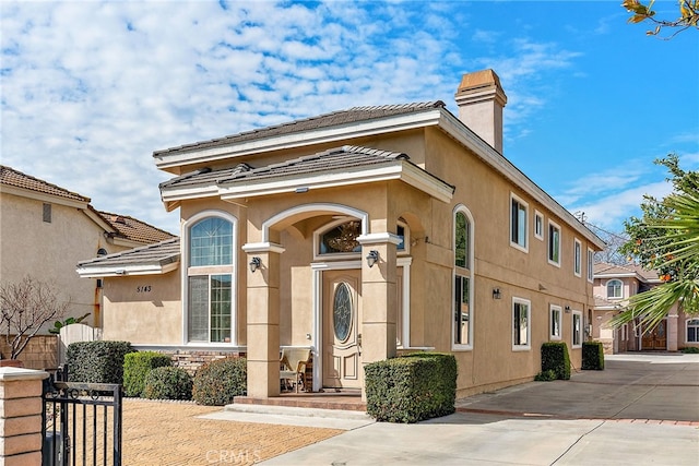 view of front of property featuring a chimney, fence, and stucco siding