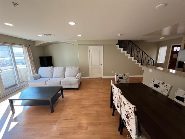 living room featuring recessed lighting, visible vents, light wood-type flooring, baseboards, and stairs