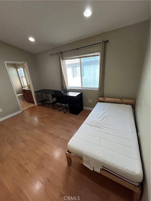 bedroom featuring baseboards, ensuite bathroom, light wood-style flooring, and recessed lighting