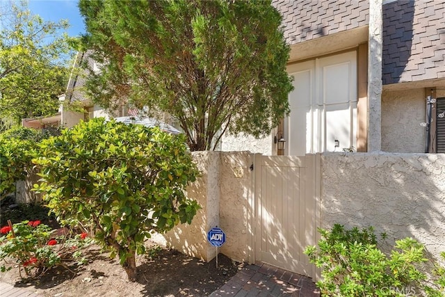 view of home's exterior featuring a shingled roof, fence, and stucco siding