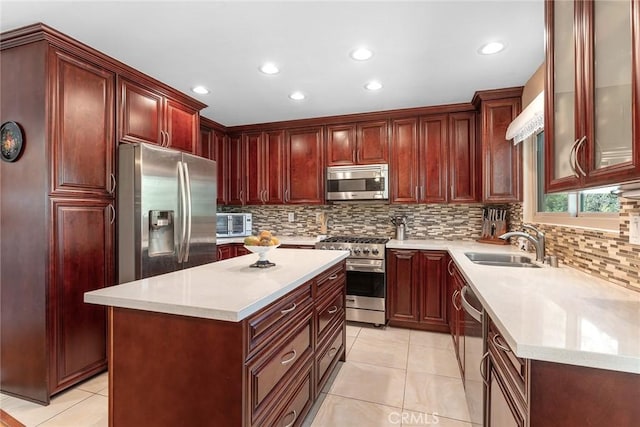 kitchen with light countertops, appliances with stainless steel finishes, a kitchen island, and a sink