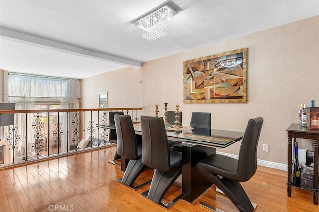 dining area with baseboards, beamed ceiling, an inviting chandelier, and light wood-style floors