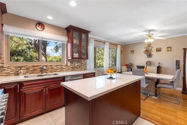 kitchen with a center island, tasteful backsplash, light countertops, glass insert cabinets, and a sink