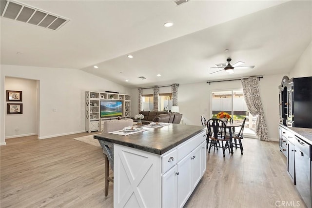 kitchen featuring visible vents, dark countertops, open floor plan, a center island, and white cabinetry