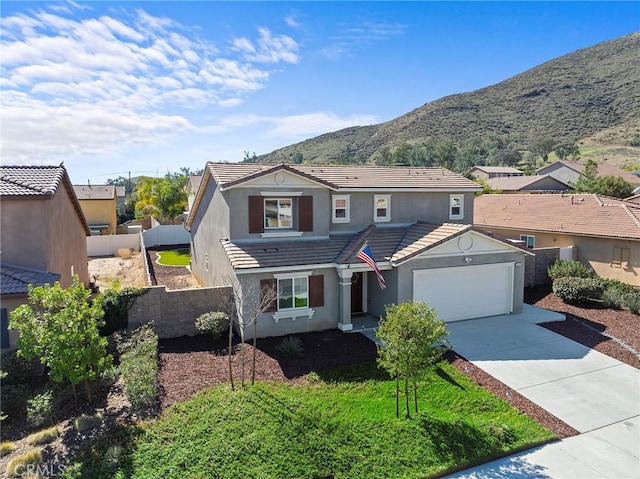 traditional home with an attached garage, a mountain view, a tile roof, concrete driveway, and stucco siding