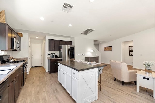 kitchen featuring black appliances, dark countertops, visible vents, and a center island