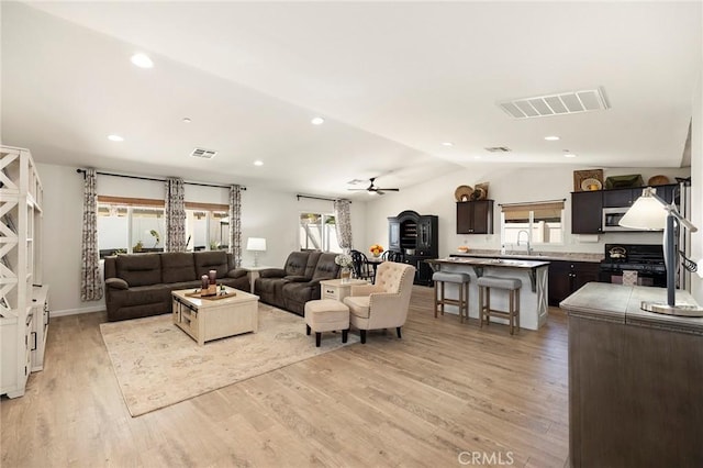 living room with light wood-type flooring, lofted ceiling, visible vents, and recessed lighting