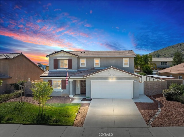 traditional-style house with an attached garage, a tile roof, fence, concrete driveway, and stucco siding