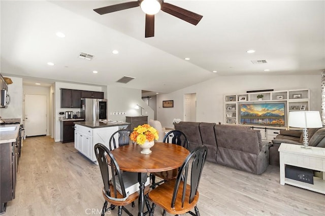 dining room featuring vaulted ceiling, light wood finished floors, stairway, and visible vents