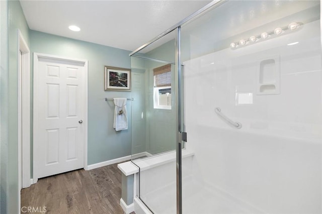 bathroom featuring a stall shower, baseboards, and wood finished floors