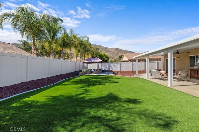 view of yard featuring a fenced backyard, a mountain view, an outdoor living space, a gazebo, and a patio area