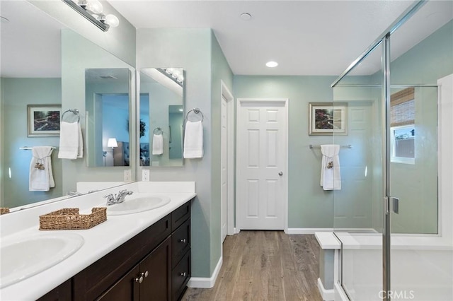 full bath featuring a shower stall, baseboards, a sink, and wood finished floors