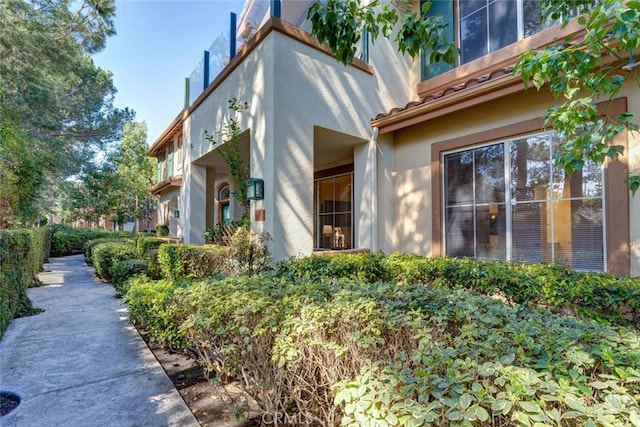 view of side of property featuring a tile roof and stucco siding