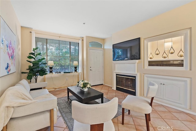 living area featuring light tile patterned flooring and a glass covered fireplace