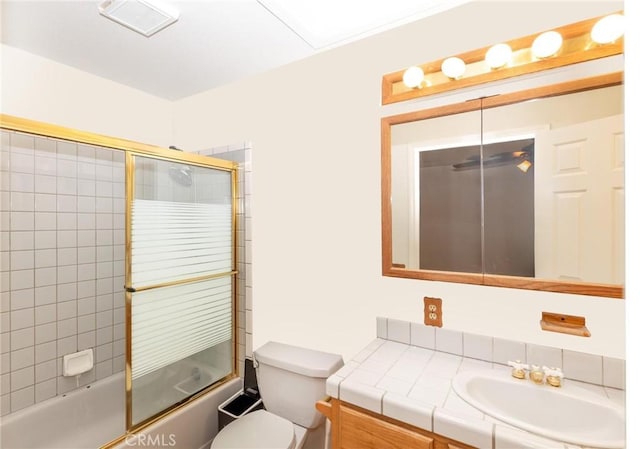 bathroom with enclosed tub / shower combo, vanity, and toilet