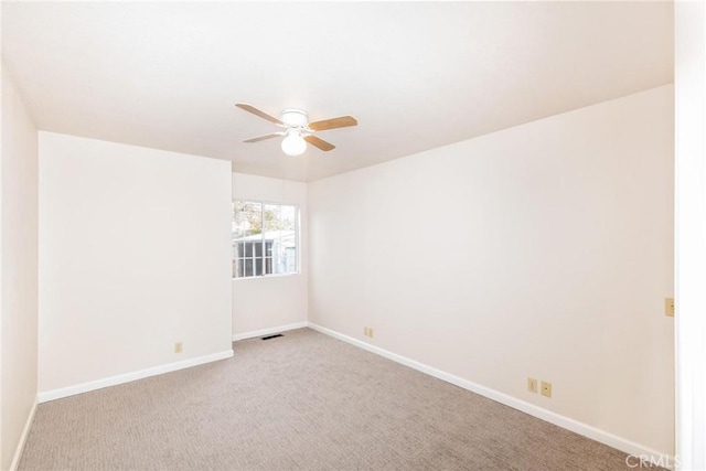 empty room featuring light carpet, visible vents, a ceiling fan, and baseboards