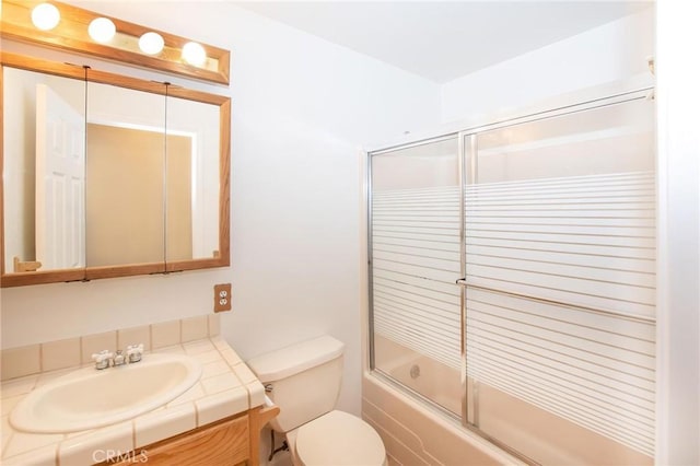 full bath with toilet, bath / shower combo with glass door, and vanity