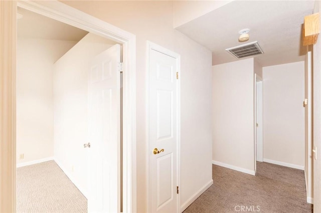 hall featuring light colored carpet, visible vents, and baseboards