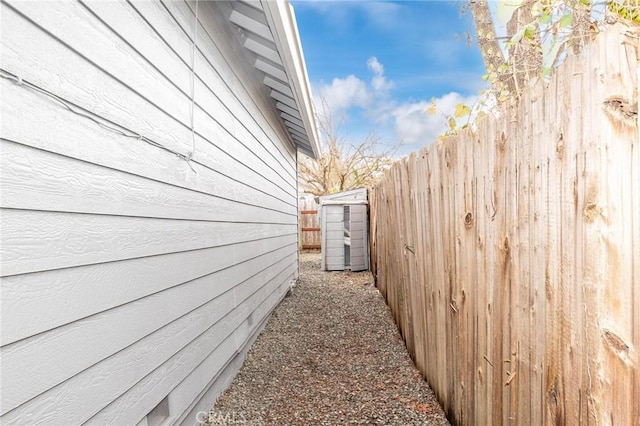 view of side of property with an outbuilding, fence, and a storage shed