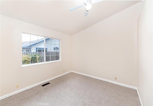 empty room featuring lofted ceiling, light colored carpet, a ceiling fan, baseboards, and visible vents