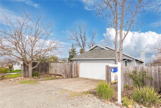 garage featuring driveway and fence