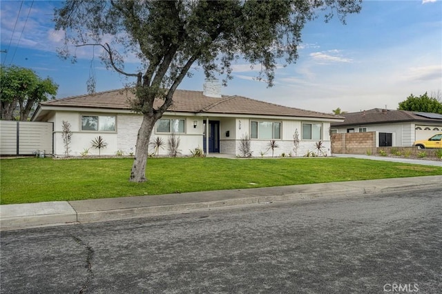 ranch-style home with a front lawn, fence, and stucco siding